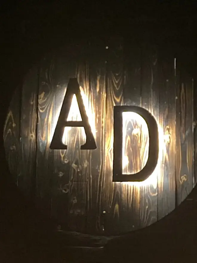 The backlit AD sign carved into the speakeasy wall