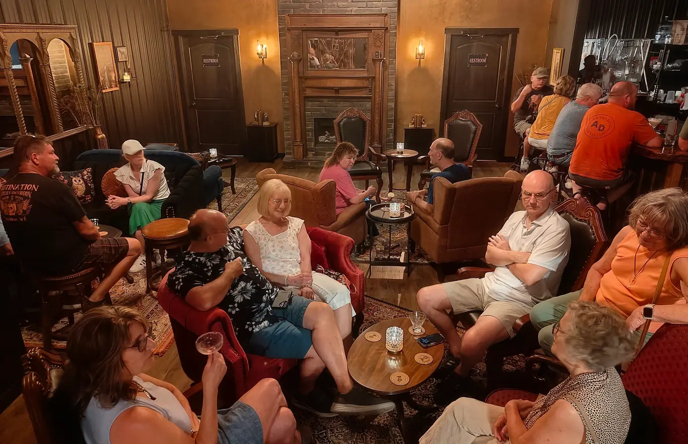 Guests gathered on velvet sofas and armchairs around the parlor fireplace