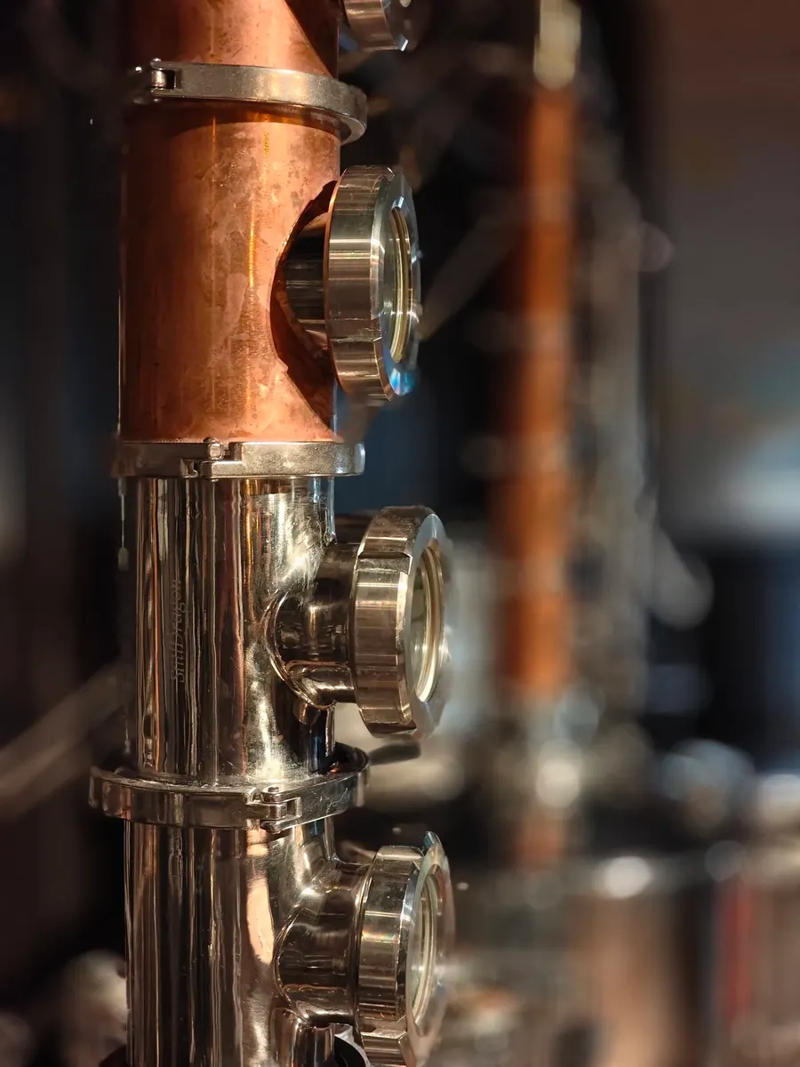 Close detail of a copper still column and its sight glasses